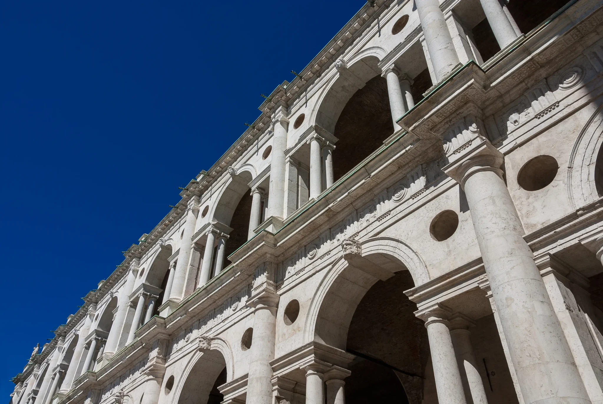 Facciata monumentale con colonne e archi sotto un cielo blu.