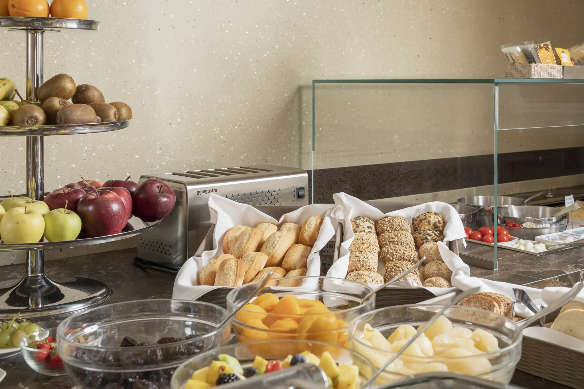 Buffet per colazione con frutta fresca, pane, affettati e formaggi.