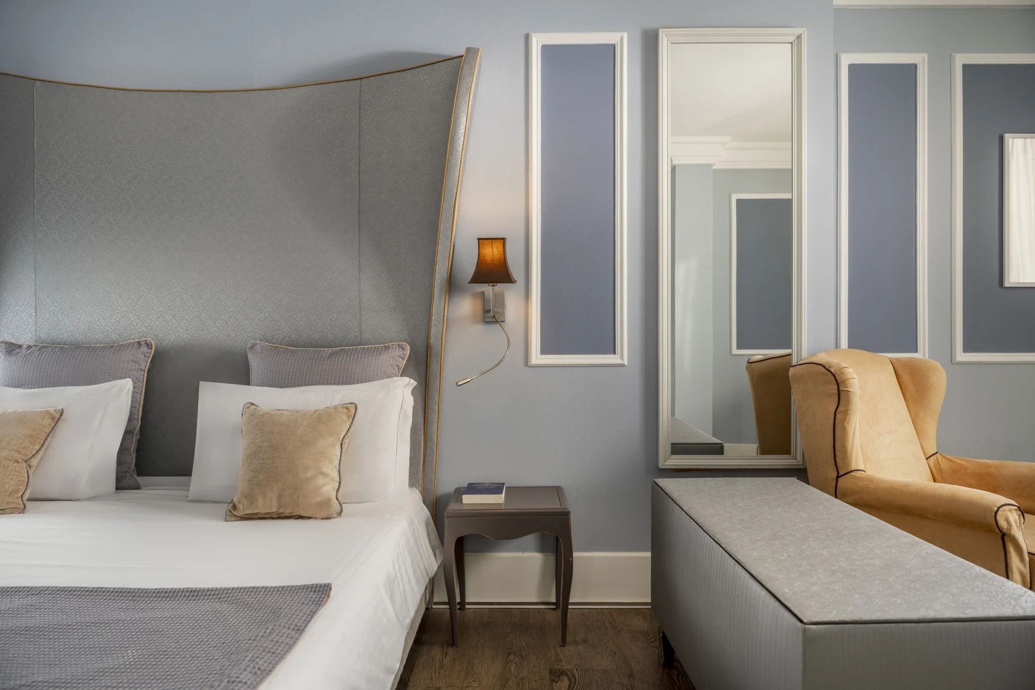 Camera da letto elegante con letto matrimoniale, poltrona gialla e decorazioni murali.