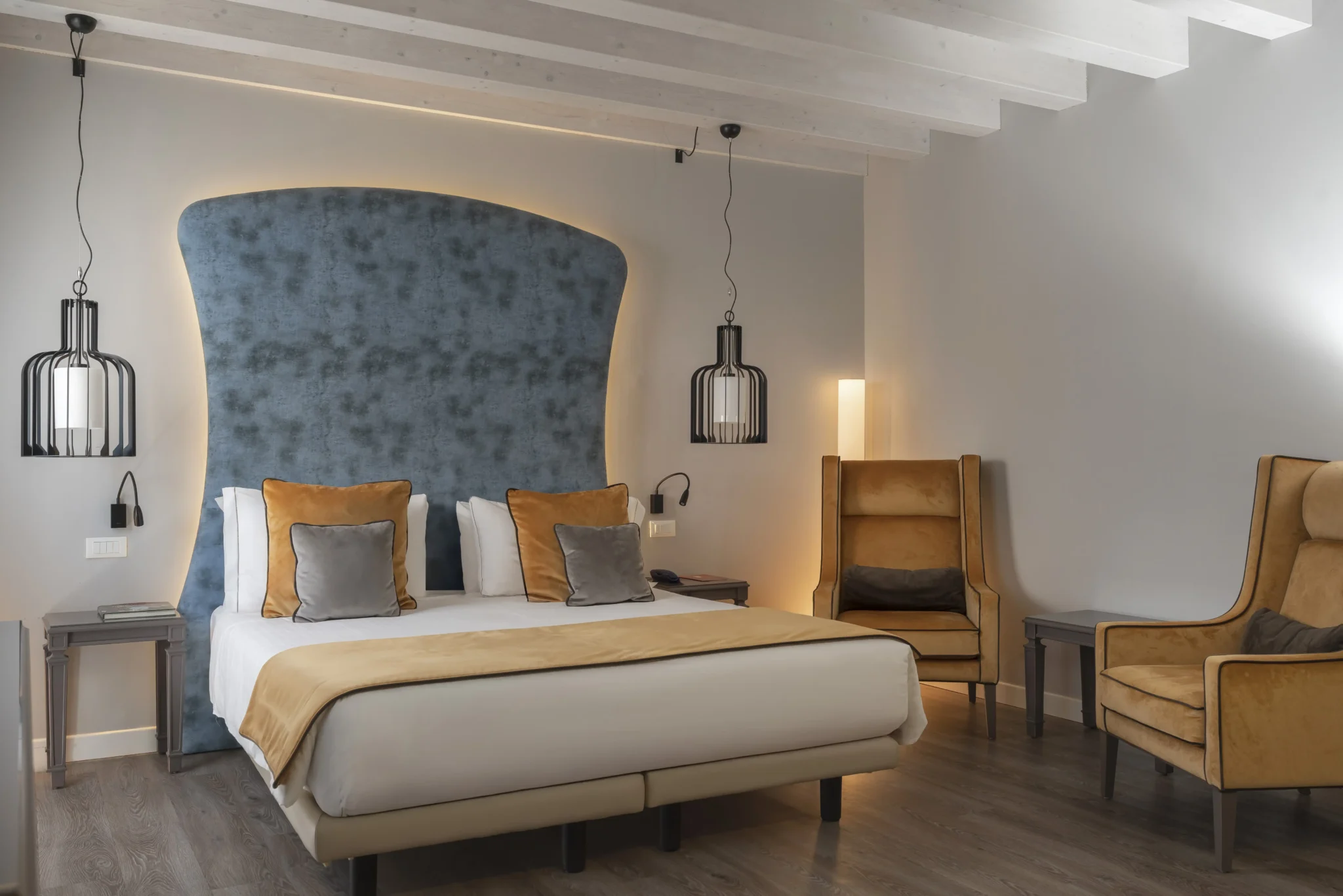 Camera da letto moderna con letto matrimoniale, sedie accoglienti e illuminazione elegante.