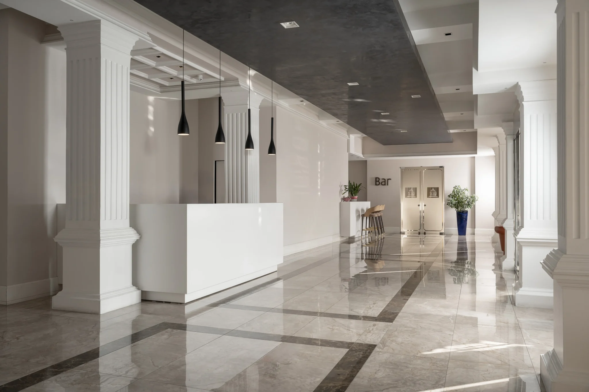 Hall d'albergo elegante con colonne bianche e pavimento in marmo lucido.
