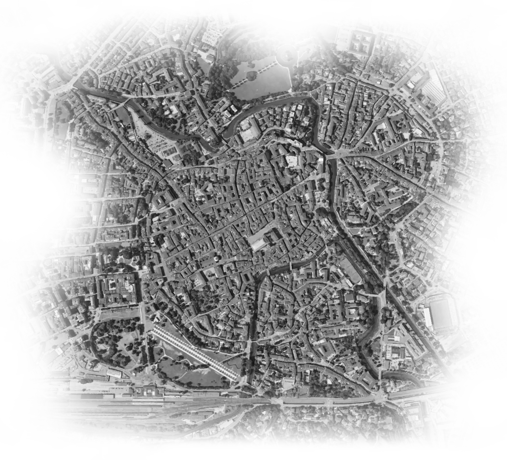 Immagine aerea in bianco e nero di un centro urbano denso con strade tortuose e spazi verdi.
