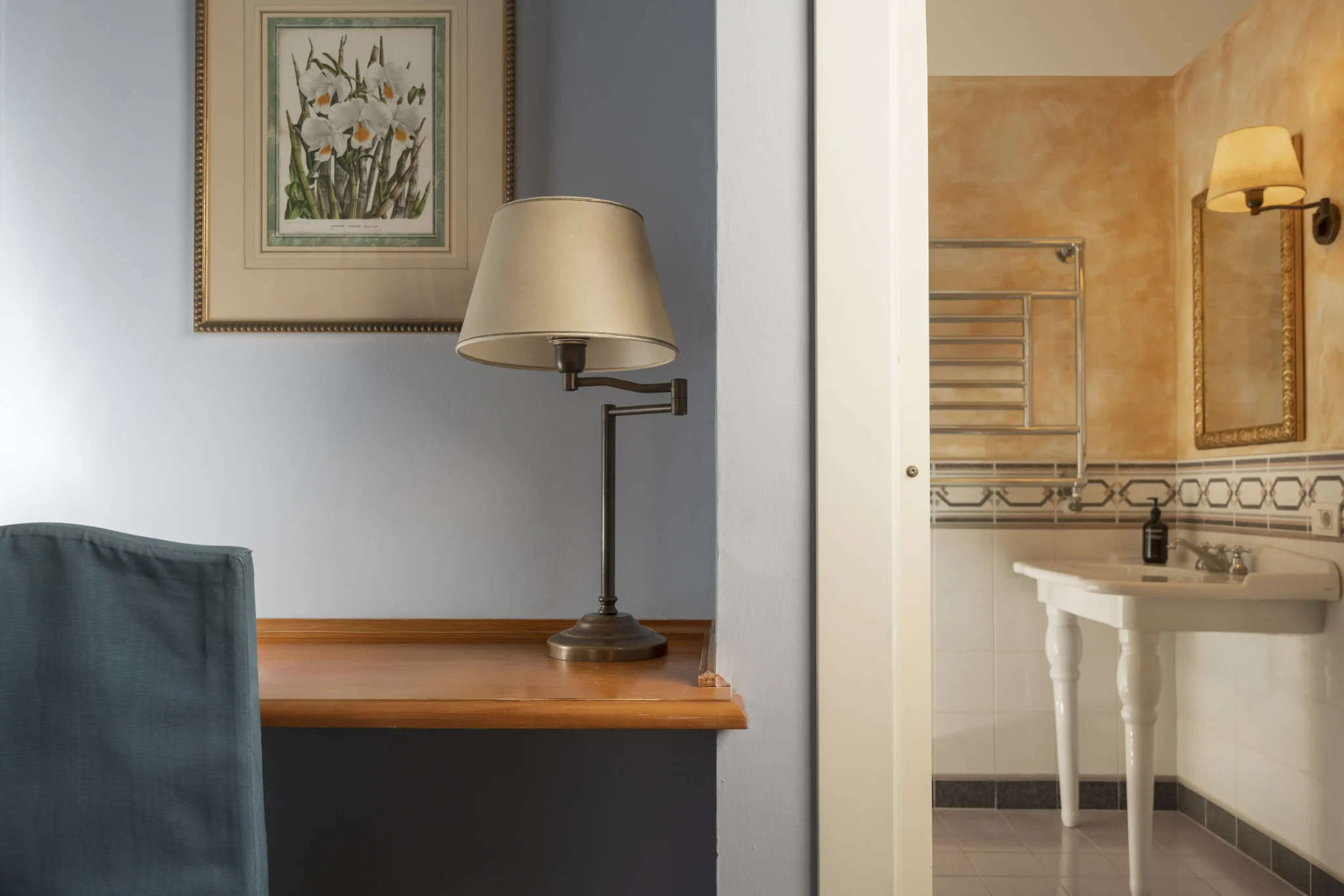 Una lampada su una scrivania accanto a un bagno con pareti color pesca.